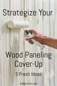 Hand painting over wood paneling with a white paint roller. Text reads: "Strategize Your Wood Paneling Cover-Up - 5 Fresh Ideas". Wood Paneling Wallpaper, Cover Up Wood Paneling, Covering Paneling Walls Ideas, Update Wood Paneling, Paneling Walls Makeover, Painting Paneling Walls, Wood Paneling Walls, Painting Fake Wood, Painting Paneling