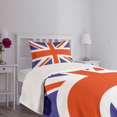 a bed with an orange, white and blue comforter on it in a bedroom