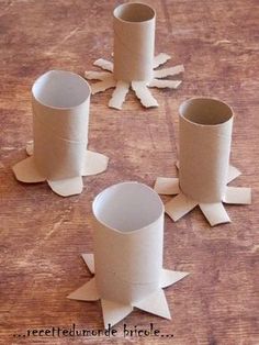 four paper cups sitting on top of a wooden table next to cut up pieces of paper