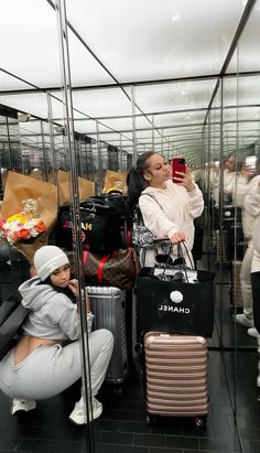 a woman taking a selfie with her cell phone in front of some suitcases