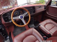 the interior of an old car with leather seats and steering wheel, showing the dashboard