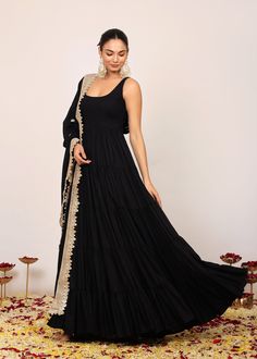 *Immerse yourself in the sophistication of this solid black Anarkali kurta, designed to be both a statement piece and a canvas for your individual style.  *The round neckline of the Anarkali kurta is an embodiment of classic charm, elegantly fitted at the bust to enhance your natural silhouette.  *The coordinating dupatta, adorned with intricate gotta work along the border, adds a touch of artisanal flair.  *It is not just an accessory; it's a complementary masterpiece that frames the ensemble w Festive Black Dress With Self Design, Anarkali Black Salwar Kameez With Self Design, Black Anarkali Set With Dabka For Diwali, Black Dresses With Pallu For Eid, Black Dabka Anarkali Set For Diwali, Black Bollywood Dress With Self Design, Black Anarkali Style Sharara In Georgette, Black Semi-stitched Dress For Diwali, Semi-stitched Black Dress For Diwali