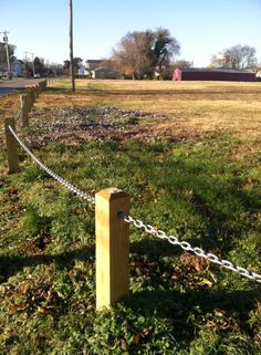 a chain link fence in the middle of a grassy field