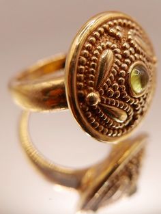 Vintage 14 carat gold Etruscan Revival ring with bezel set peridot gemstone and ornate granulation on medallion style head. Beautiful artisan piece with exquisite attention to detail including etching on underside of head.  Stamped 14K Excellent vintage condition Ring size: US 7 Head diameter: 2.2 cm / 0.7 inch Weight: 2.46 grams ☞ Please view my shipping and sales policies and ✎ Contact me with questions prior to purchase...all sales are final. http://www.etsy.com/shop/Andeebird/policy Elegant Domed Jewelry With Bezel Setting, Gold Byzantine Jewelry With Bezel Setting, Luxury Gold Peridot Jewelry, Luxury Gold Jewelry With Peridot, Ornate Yellow Gold Filigree Ring With Gemstone, Antique Gold Jewelry With Stone Setting, Elegant Green Domed Jewelry, Gold Byzantine Jewelry With Cabochon, Byzantine Gold Cabochon Jewelry