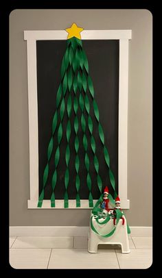 a paper christmas tree sitting on top of a table next to a white framed photo