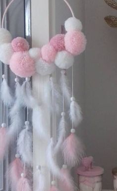 a pink and white mobile with pom - poms hanging from it's sides