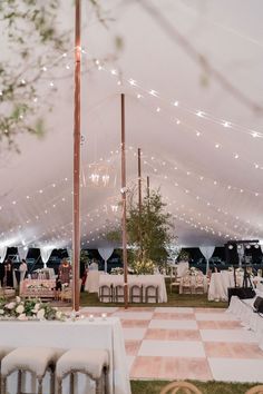 the inside of a tent with tables and chairs set up for an outdoor wedding reception