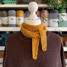 a mannequin wearing a brown sweater with a yellow scarf around it's neck