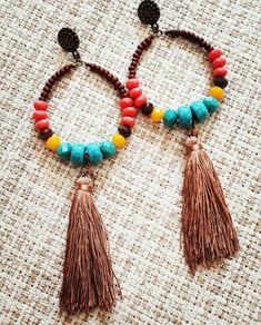 two bracelets with beads and tassels on top of a cloth tablecloth