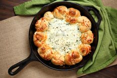 a cast iron skillet filled with bread and cheese on top of a green towel