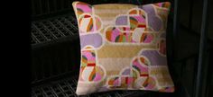 a colorful pillow sitting on top of a metal rack next to a black wall and floor