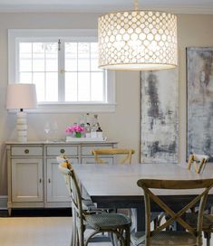 a dining room table with four chairs and a lamp hanging from the ceiling over it