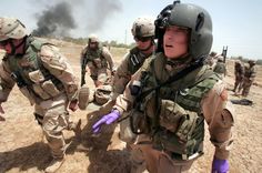 some soldiers are in the dirt and one is pointing to something on the ground with his hand