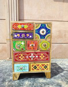 a multicolored wooden cabinet with many different designs on the front and side panels