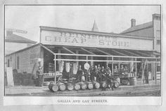 an old black and white photo of people standing in front of a store with barrels