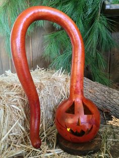 an orange pumpkin shaped vase sitting on top of hay