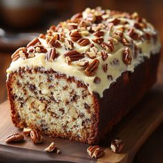 a loaf of cake sitting on top of a cutting board with pecans around it