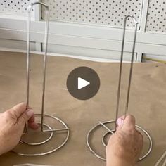 two hands holding metal objects on top of a table