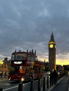 the big ben clock tower towering over the city of london at dusk with people walking on the sidewalk