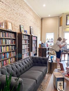 two children are standing in the middle of a library with bookshelves and couches