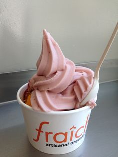 an ice cream sundae with pink frosting in a white cup