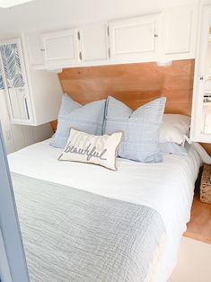 a bed with blue and white pillows on top of it in a bedroom next to a closet