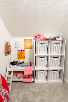 a room with white shelving and lots of storage bins on the floor in front of it