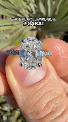 a person holding a diamond ring in their hand with the words watch this oval diamond brow 2 carat