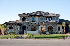 a large house that is in the middle of a street with palm trees around it