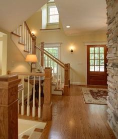 an open floor plan with wood floors and stone wall in the center, along with stairs leading up to second story