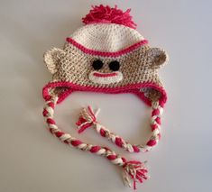 a crocheted hat with a monkey face on the front and pink trim around the brim