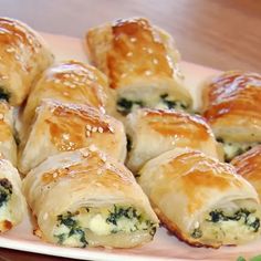 there are many rolls with cheese and spinach on the plate