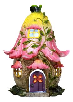 a pink and yellow fairy house with flowers on it's roof, sitting in front of a white background