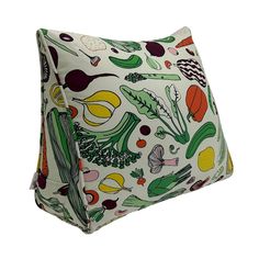 a white pillow with colorful vegetables and fruits printed on the front, sitting on a white surface