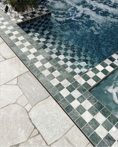 an empty swimming pool with tiled flooring and palm trees in the background, surrounded by stone pavers