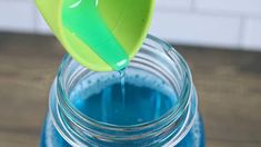 a plastic spoon pouring blue liquid into a jar