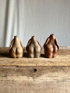 three small clay sculptures sitting on top of a wooden table