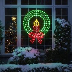 a lighted christmas wreath in front of a window