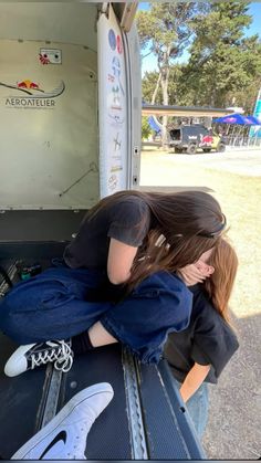 two people sitting in the back of a truck with their hands on each other's backs