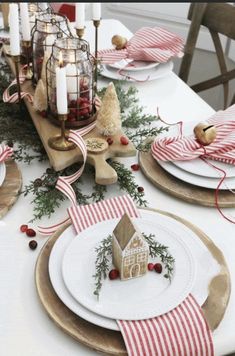 a table set for christmas with plates, napkins and candle holders on top of it