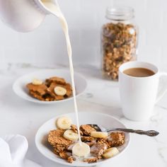 a person pouring milk onto a plate of cereal with bananas and granola on the side