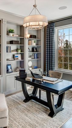 a home office with built - in bookcases and a chandelier