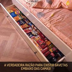 an open drawer in the middle of a bed with snacks and drinks on it's bottom shelf