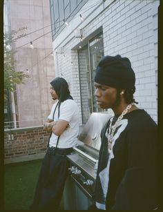 two people standing next to each other in front of a building