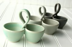 four ceramic cups are arranged in the shape of two swan's beaks and one is shaped like a bird