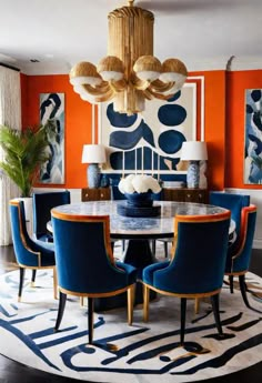 a dining room with orange walls and blue chairs around a round table surrounded by art