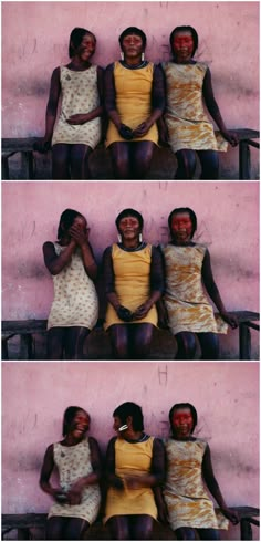 three women sitting next to each other in front of a pink wall and one is holding her head