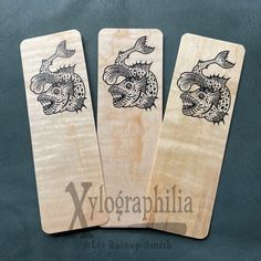 three wooden playing cards with designs on them