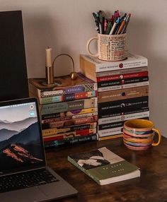 a laptop computer sitting on top of a wooden desk next to a stack of books