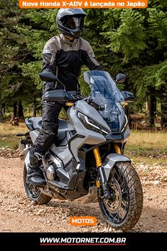 a man riding on the back of a motorcycle down a dirt road in front of trees